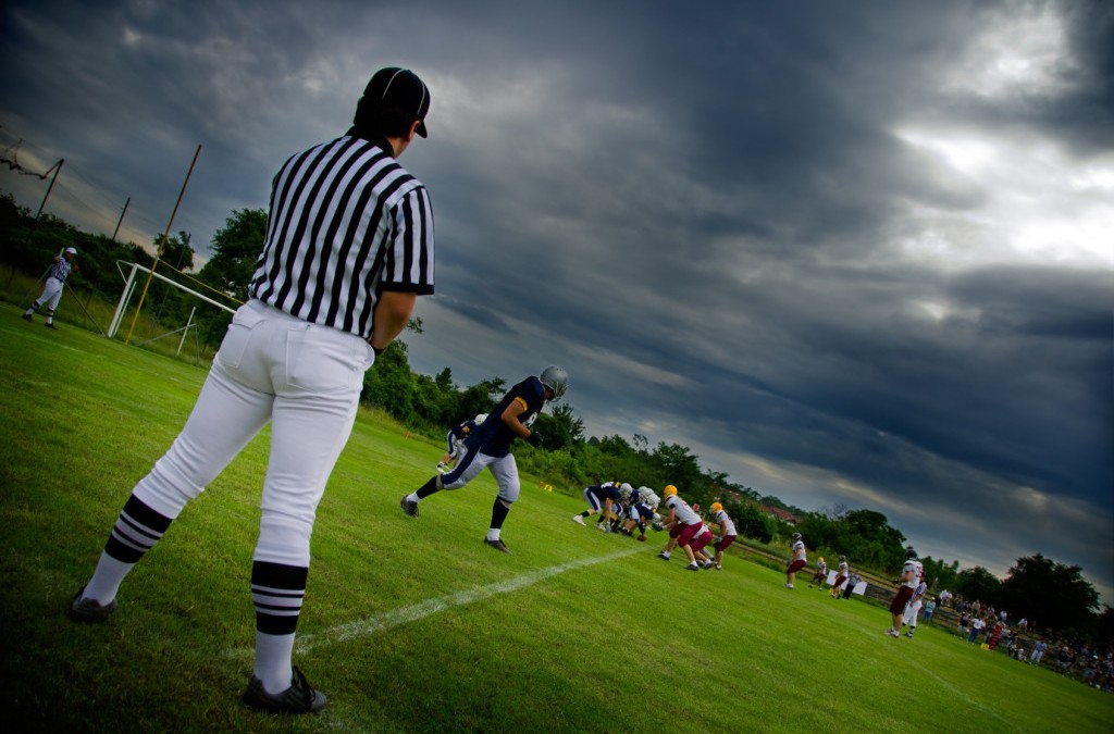 American football referee umping a game on a dark stormy night