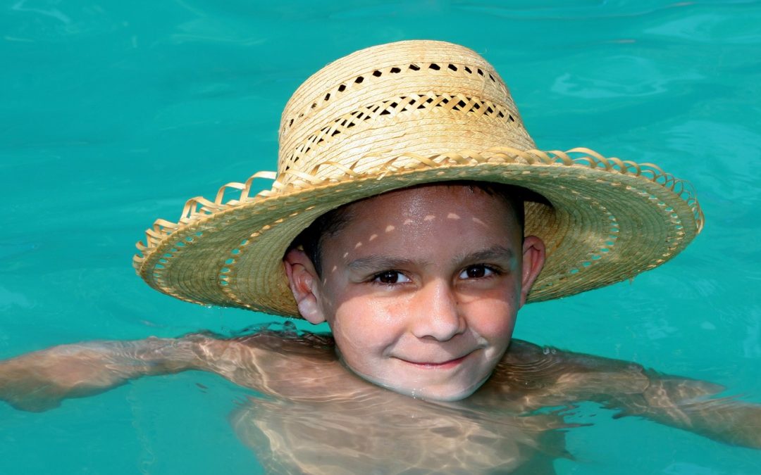 6 Ways to Stay Cool and Save Energy | Close-up of small boy with sunhat swimming in pool